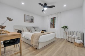 Ein modernes Schlafzimmer mit Bett, Schreibtisch, Stuhl und Deckenventilator.