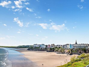 A coastal town with a sandy beach, buildings, and a church. - 3 Bed in Tenby (oc-fb231) (Tenby)