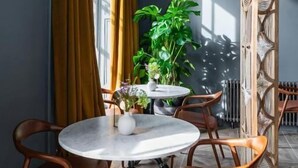 Et spiseområde med et rundt bord, stole, en potteplante og en radiator.