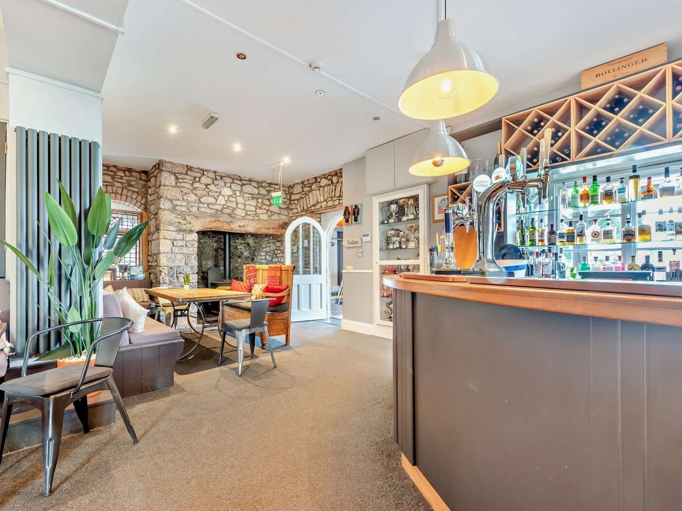 Eine Bar mit einer Steinsäule, einem Weinschränkchen aus Holz und einer Auswahl an Flaschen.
