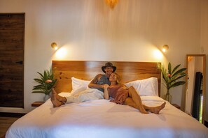 A bed with a wooden headboard, two bedside tables with lamps, and a large mirror on the wall. - Samaya Lush Lakeside Apt - White Lotus (San Miguel)