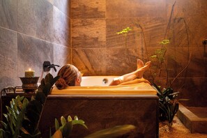 A person relaxing in a bathtub with a candle and plants around. - Samaya Lush Lakeside Apt - White Lotus (San Miguel)