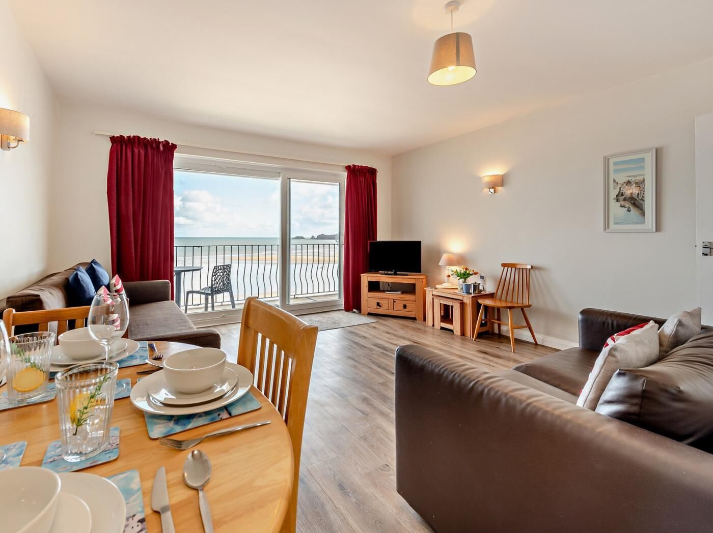 Un salon moderne avec balcon, un coin repas et un meuble pour la télévision.