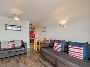 A living room with two sofas, a dining table, and a kitchen in the background. - 1 Bed in Saundersfoot (oc-fb298) (Saundersfoot)