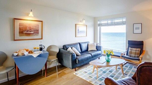 Ein Wohnzimmer mit Sofa, Sesseln, Couchtisch und Meerblick.