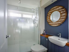 Ein modernes Badezimmer mit Duschkabine aus Glas, einer weißen Toilette und einem spiegel mit Holzrahmen über einem weißen Waschbecken.
