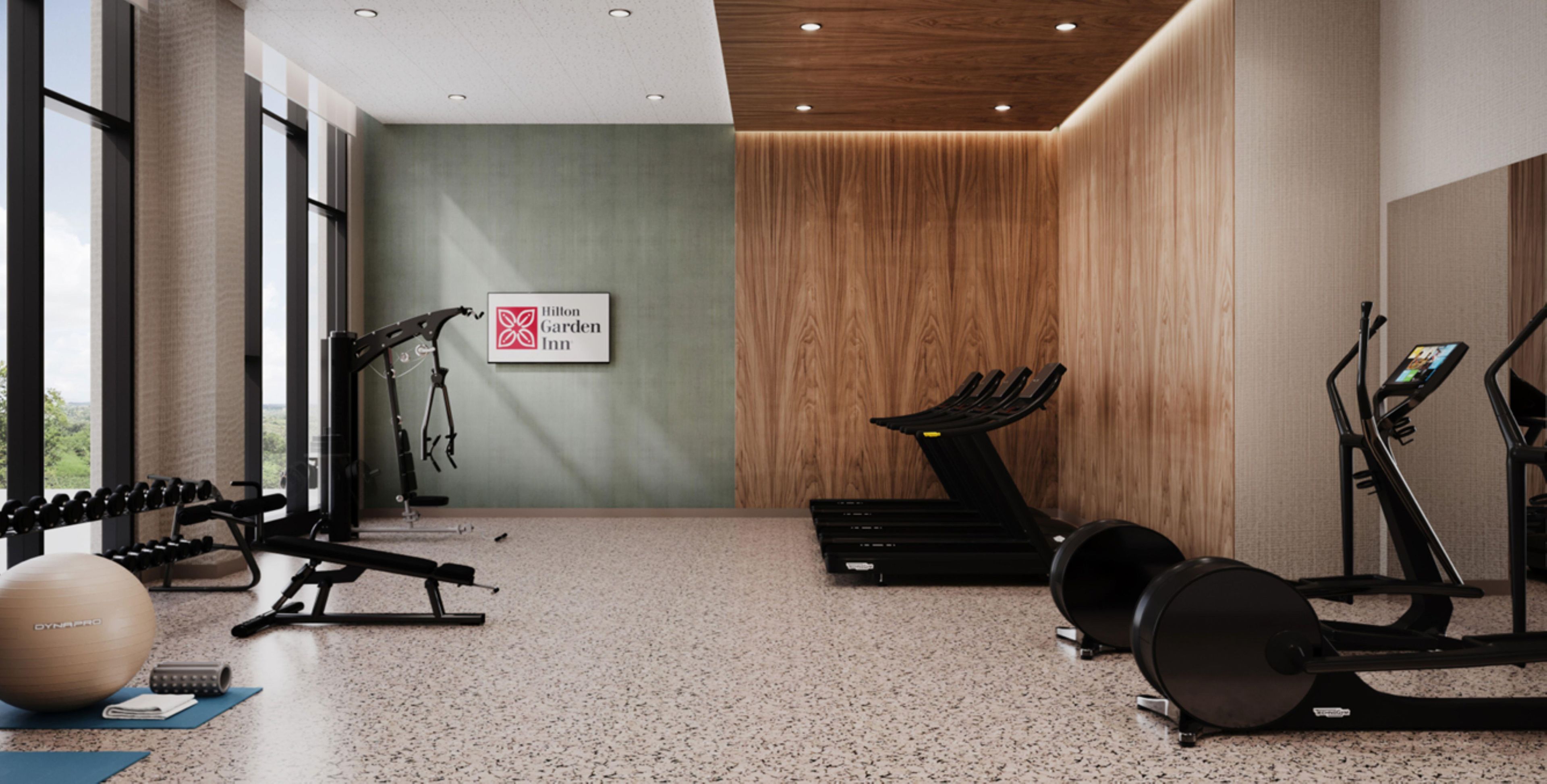 Ein Fitnessraum mit Trainingsgeräten, Laufband und einem Schild für Hilton Garden Inn.