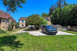 A residential area with stone houses, a gravel driveway, and a parked car. - Gite de Pierre, a vacation rental in a restored farmhouse. In the heart of the Périgord Noir (Carsac-Aillac)