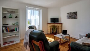 Een woonkamer met een open haard, een televisie, een boekenkast en een bijzettafeltje.