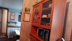 A kitchen with wooden cabinets, a microwave, a sink, and a radiator. - Cozy one bedroom tiny house. (Colville)