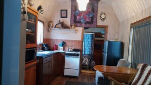 A compact kitchen with wooden cabinets, a stove, and a refrigerator. - Cozy one bedroom tiny house. (Colville)