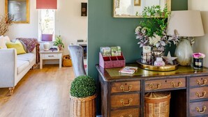 Un salon confortable avec un canapé, un bureau, une chaise, une commode et un miroir.
