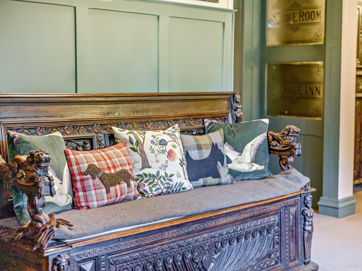 A vintage-style sofa with ornate carvings and multiple decorative pillows.