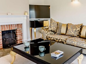 A living room with a fireplace, a sofa, a coffee table, and a television.