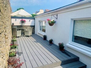 Eine Holzterrasse mit Gartenmöbeln, Blumentöpfen und hängenden Blumenkörben.
