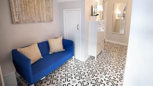 A hallway with a blue sofa, a white cabinet, a mirror, and patterned floor tiles. - 2 Bed in Tenby (oc-fb261) (Tenby)