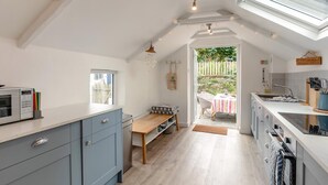 Une cuisine moderne avec des meubles gris, une table en bois et une vue sur l’extérieur.