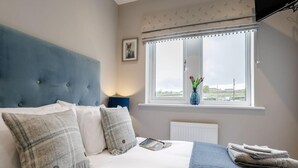Ein Schlafzimmer mit Bett, Fenster mit Blick, Heizkörper und einem Bild an der Wand.