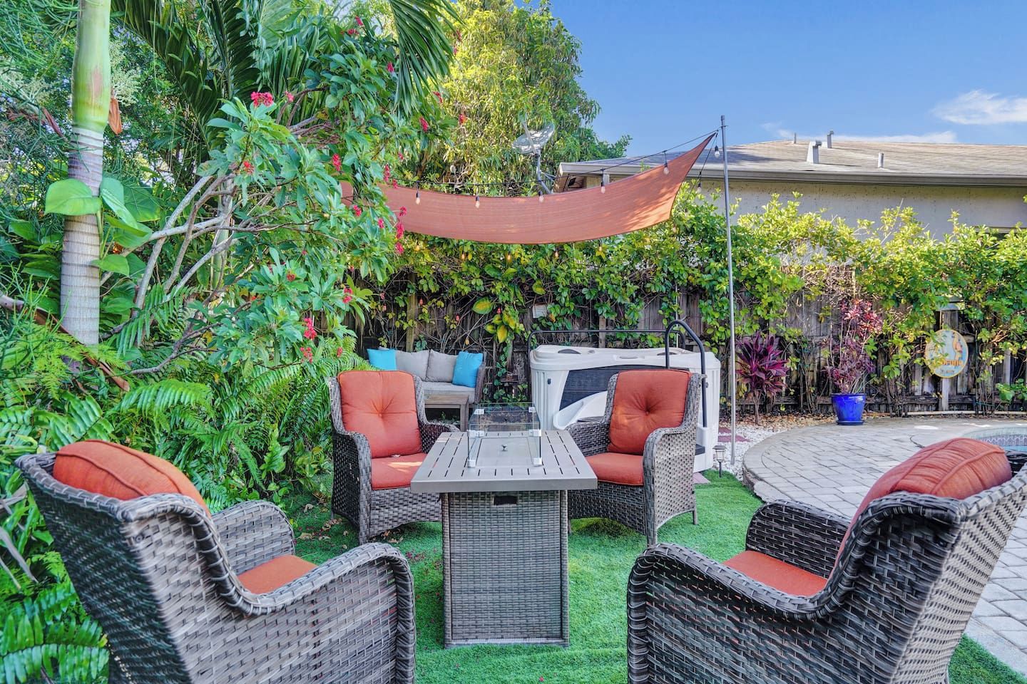 An outdoor patio with wicker furniture, a table, and a hot tub.
