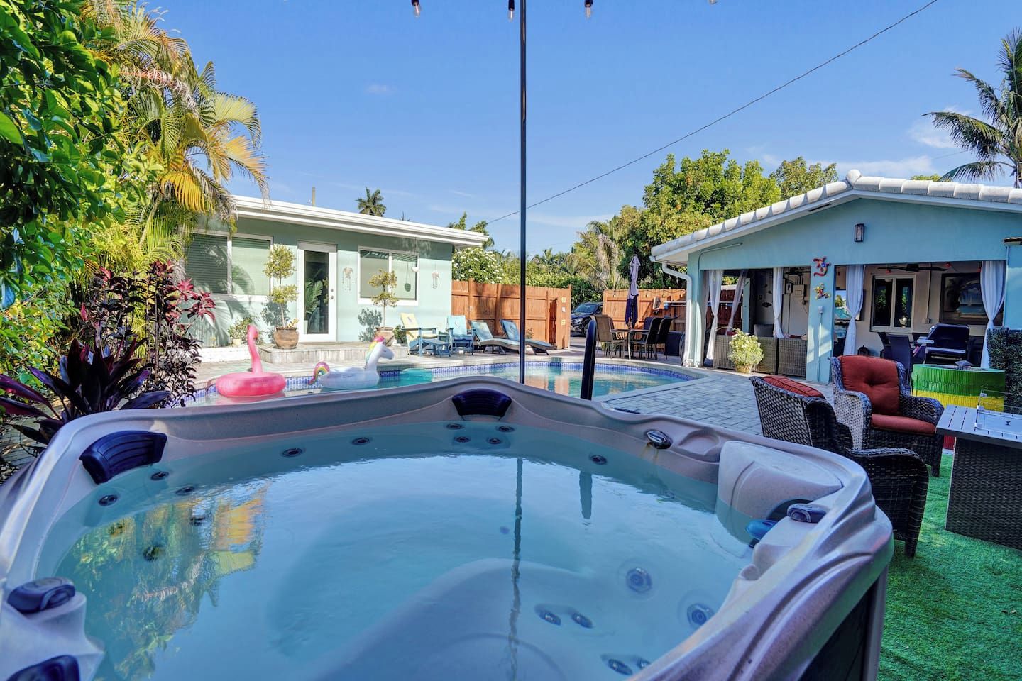 A hot tub with a pool, outdoor furniture, and a house in the background.