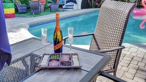 Ein Tisch mit einer Weinflasche, zwei Gläsern und einer Auswahl an Snacks am Pool.