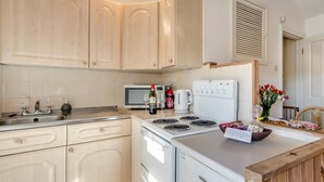 Una cucina con lavello, piano cottura, forno a microonde e mobili.