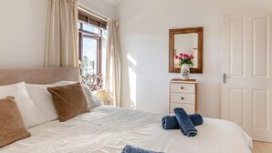 Una camera da letto con un letto, un comodino con un vaso, uno specchio e una finestra con tende.