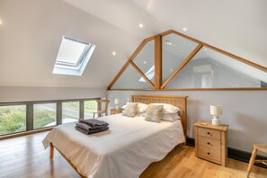 A bedroom with a large bed, a wooden nightstand, a chair, a desk, and a skylight. - 1 Bed in Little Gransden (oc-81056) (Little Gransden)