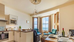 A compact kitchen with modern appliances, a dining area with a view, and a cozy seating arrangement. - 2 Bed in Tenby (oc-fb233) (Tenby)