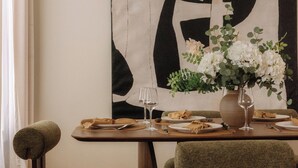 Ein Esstisch, gedeckt mit Tellern, Besteck und einer Blumenvase.