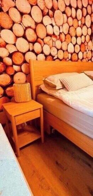 Ein Schlafzimmer mit einem hölzernen Bett, einem Nachttisch und einer Wand aus gestapelten Baumstämmen.