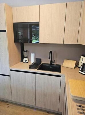 Eine kleine Küche mit einem schwarzen Spülbecken, einem Mixer und einer Kaffeemaschine.