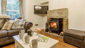 Ein gemütliches Wohnzimmer mit Kamin, Ledersofa und Couchtisch mit Tassen.