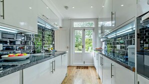 Une cuisine moderne avec des armoires blanches, des plans de travail noirs et un plancher en bois.