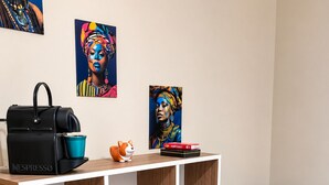 Ett rum med en bokhylla, en grön fåtölj, en svart pall och en Nespresso-kaffemaskin.