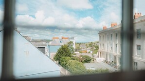 A view through a window of a cityscape with buildings, a clear sky, and a tree. - 2 Bed in Tenby (oc-fb285) (Tenby)
