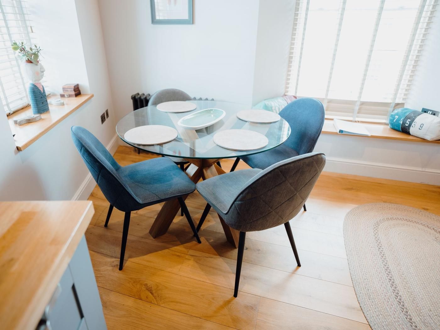 A modern dining area with a glass table and blue upholstered chairs.