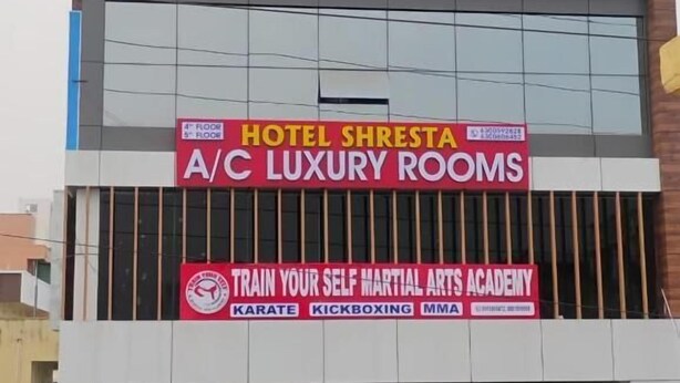 Un bâtiment portant l’enseigne « SURYA CASTLE », une publicité pour « HOTEL SHRESTA A/C LUXURY ROOMS » et une offre d’entraînement aux arts martiaux proposée par « TRAIN YOUR SELF MARTIAL ARTS ACADEMY », avec des cours de karaté, de kick-boxing et de MMA.
