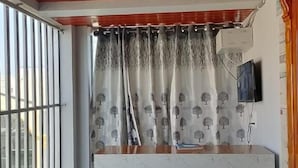 Une pièce avec un plafond en bois, un comptoir d’accueil agrémenté d’un rideau à motifs et une fenêtre avec des barreaux.
