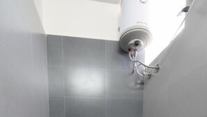Une petite salle de bain moderne équipée de toilettes, d’une douche et d’une caméra de surveillance fixée au mur.