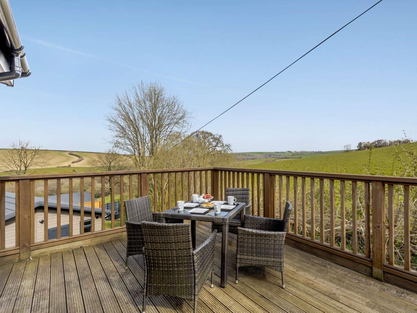 A wooden deck with a table and chairs, overlooking a rural landscape.
