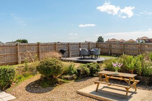 A backyard with a wooden deck, a barbecue grill, and a table with chairs. - 1 Bed in Norwich (oc-82230) (Mundesley)