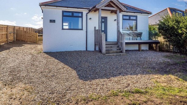 A single-story house with a gravel driveway, a wooden fence, and a small porch with steps leading to the entrance. - 1 Bed in Norwich (oc-82230) (Mundesley)