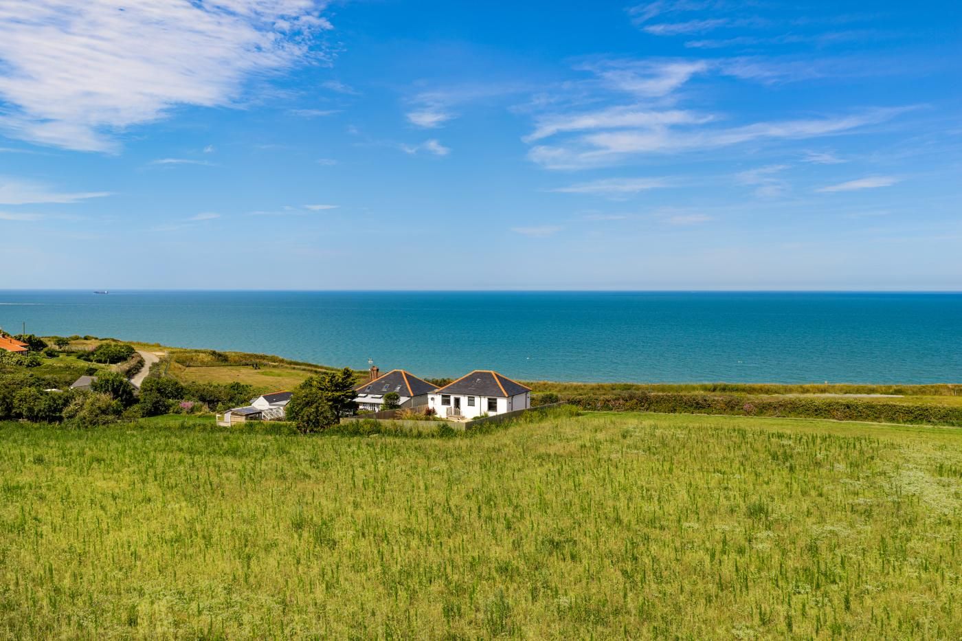 A coastal landscape with a white house and a view of the sea.
