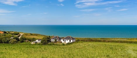 A coastal landscape with a white house and a view of the sea.