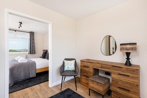 A bedroom with a bed, a chair, a wooden dresser, a mirror, and a lamp. - 1 Bed in Norwich (oc-82230) (Mundesley)