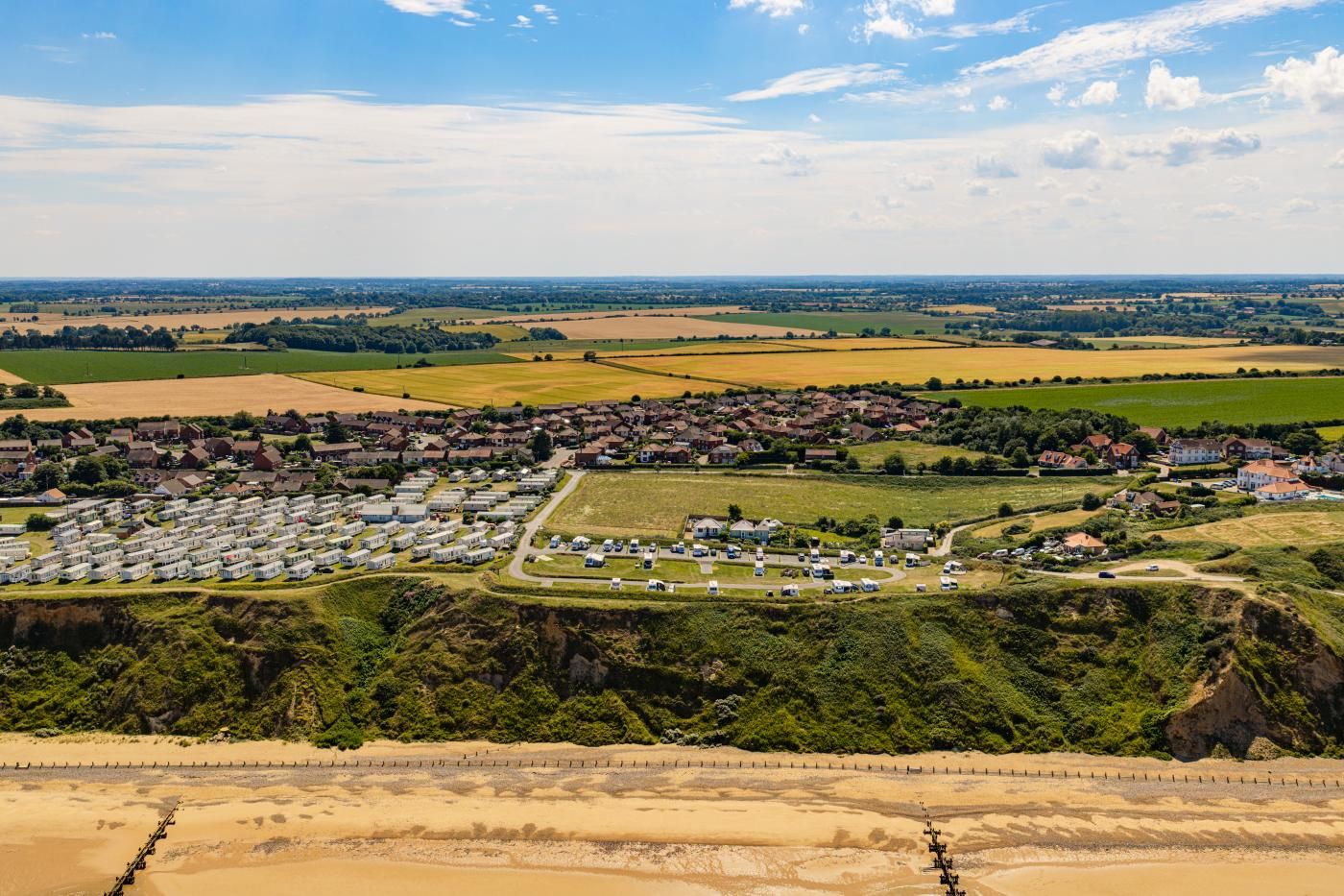 A residential area with houses, a caravan park, and open fields.