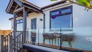 A modern house with a glass balcony, a wooden deck, and a clear sky. - 1 Bed in Norwich (oc-82230) (Mundesley)