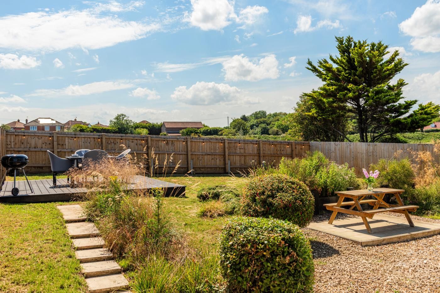 Un jardin avec un barbecue, des meubles d’extérieur et une clôture en bois.