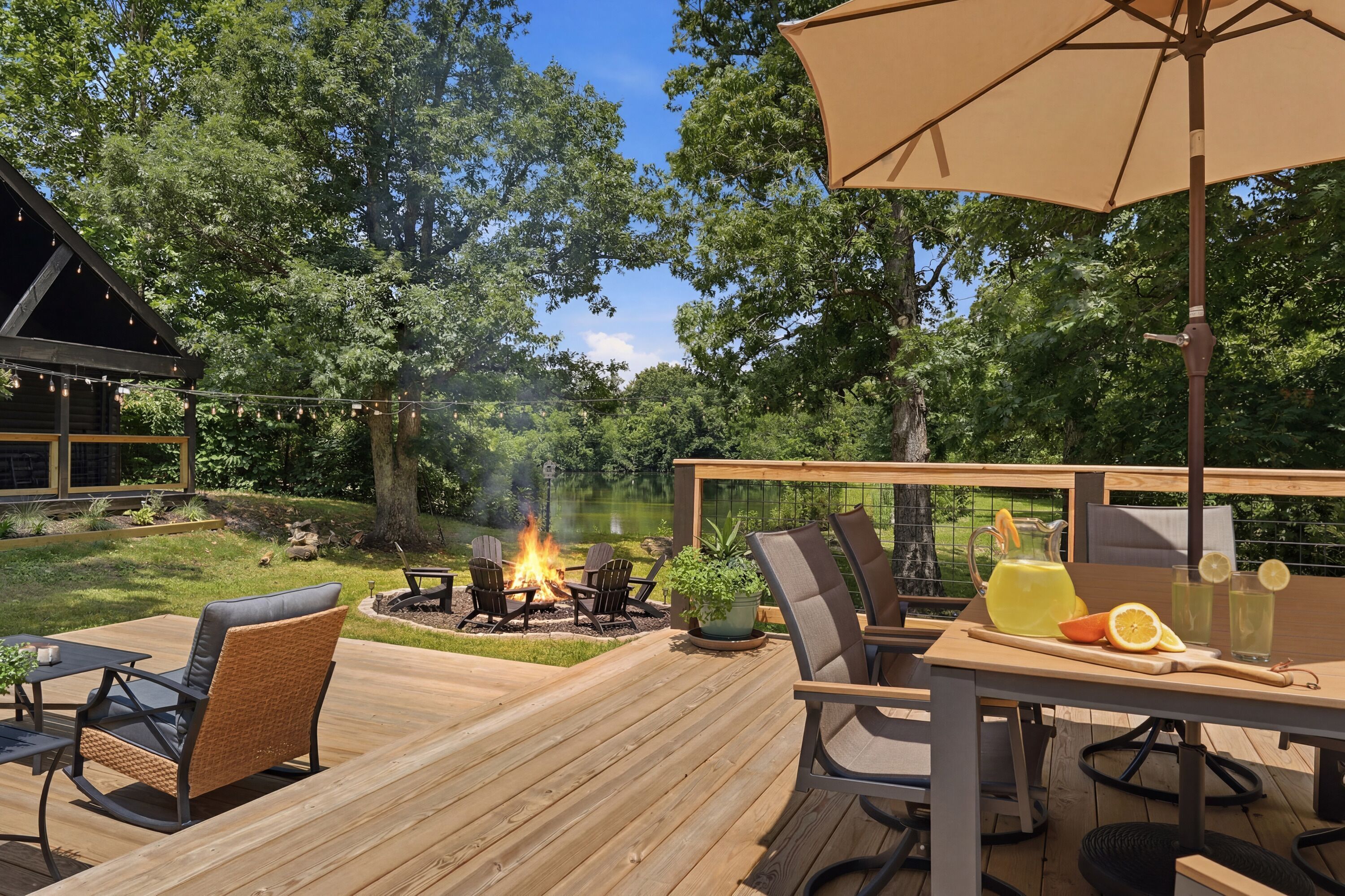 A wooden deck with outdoor furniture, a fire pit, and a table with drinks and fruit.